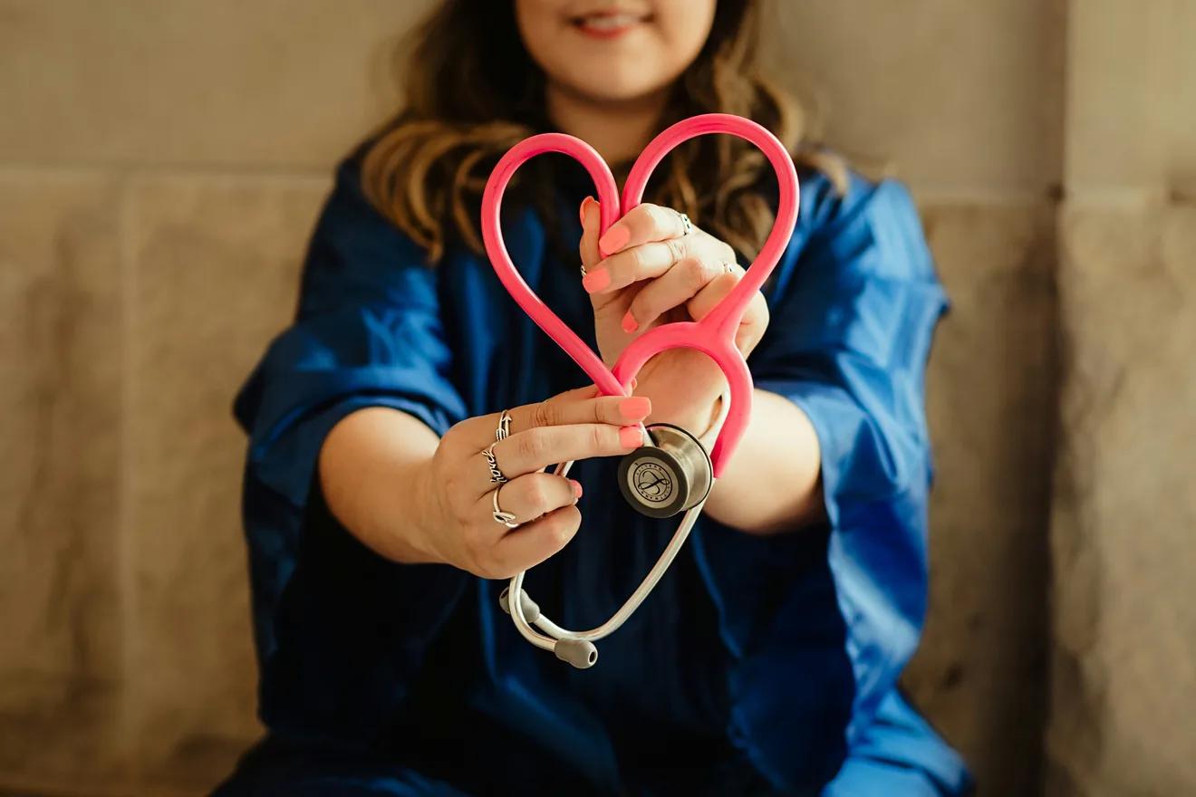 a person holding a red stethoscope curved into the shape of a heart