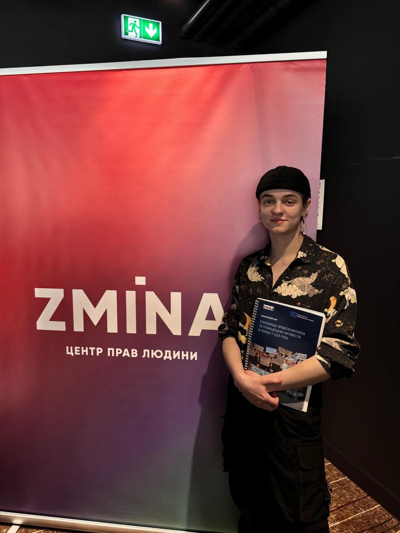 Salvador Strizh, communications manager for the NGO Resistance, stands in front of a banner featuring the ZMINA logo
