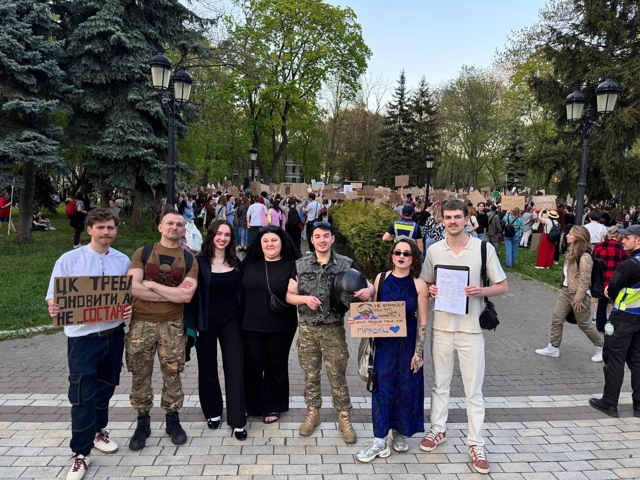 Participants in the protest from various organizations pose holding signs