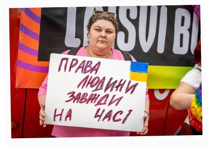 Resistance Director Kamiliia Safarova holding a “Human Rights Are Always Timely” sign